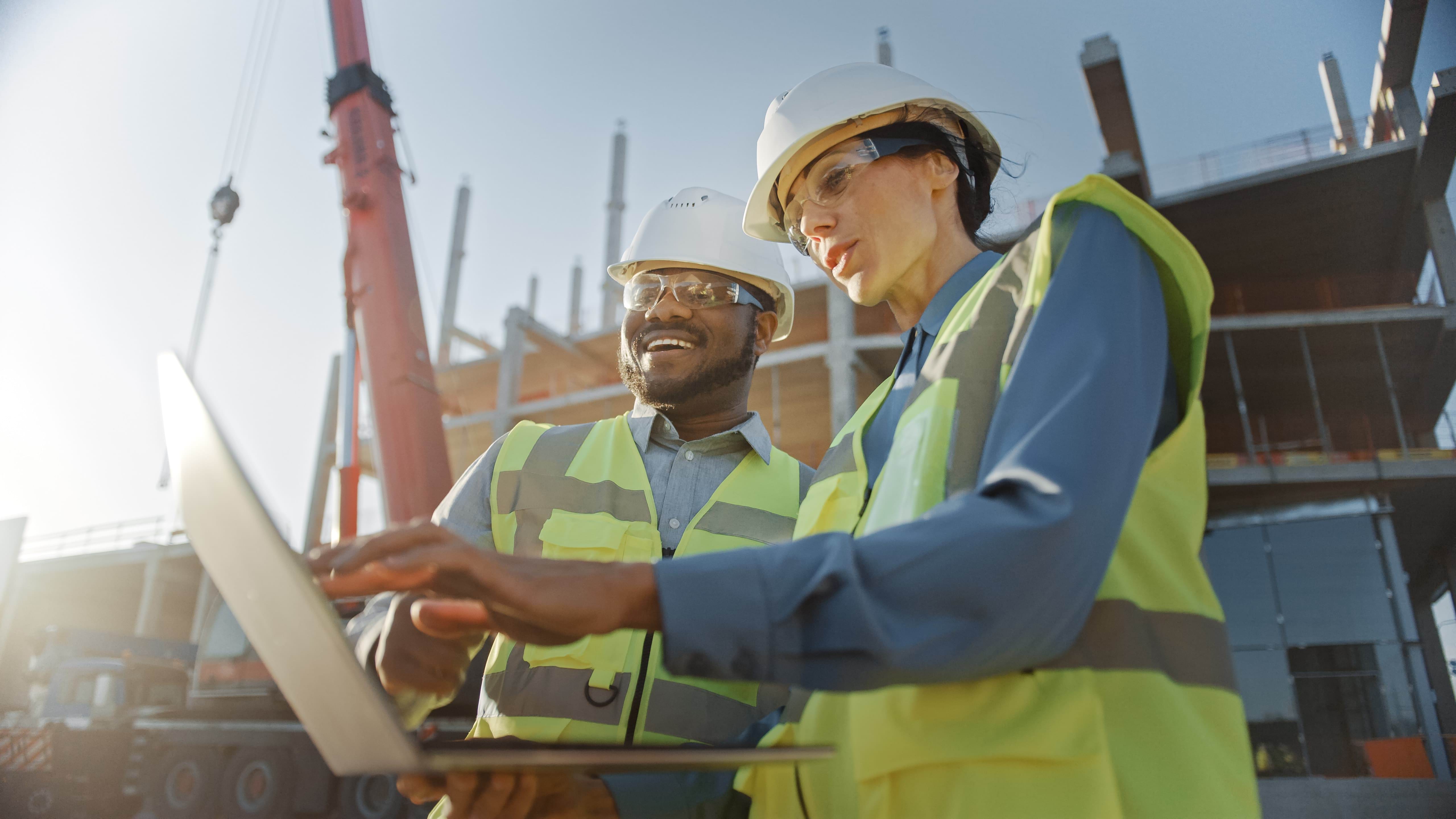 Two people in high-vis clothing looking at a laptop